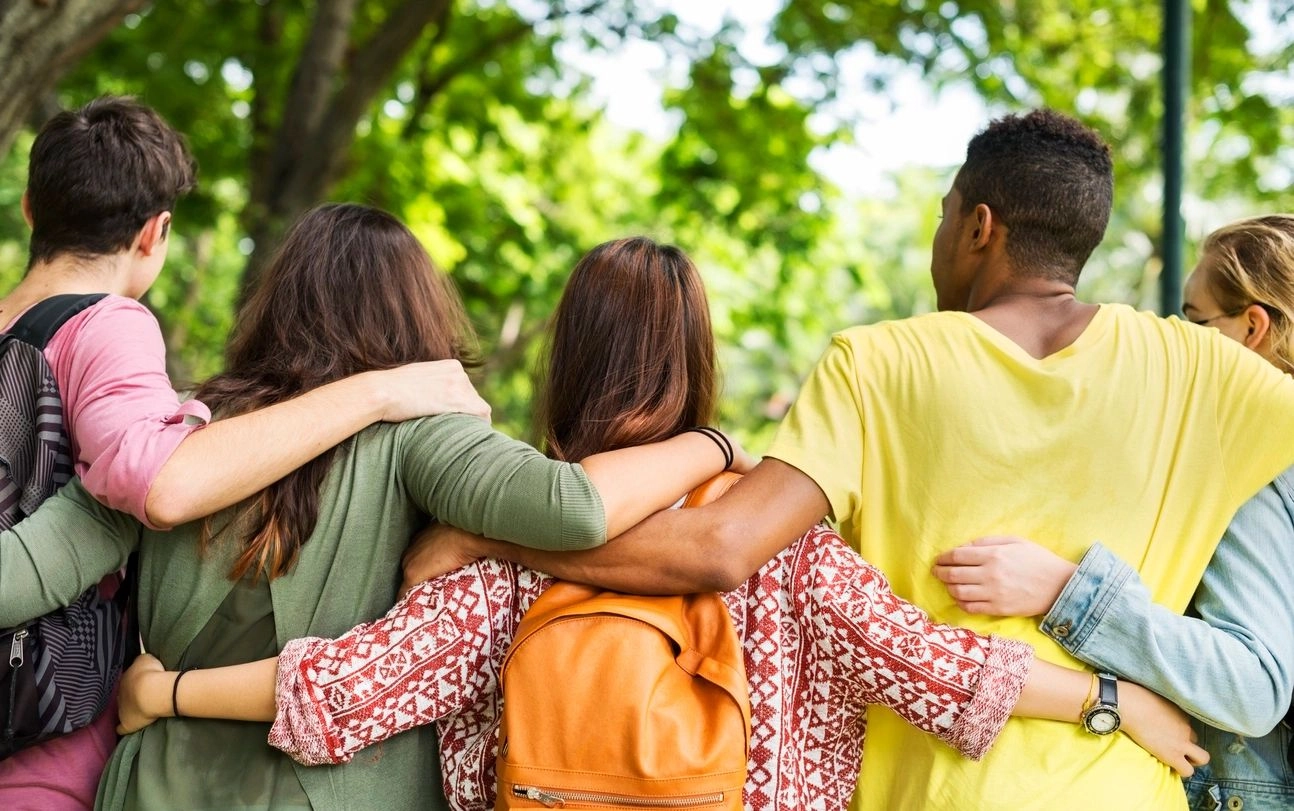 Three women hugging each other in a park.